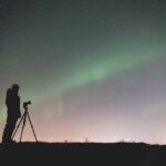 Fotógrafo capturando la aurora boreal y las estrellas en una foto.