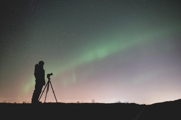 Fotógrafo capturando la aurora boreal y las estrellas en una foto.
